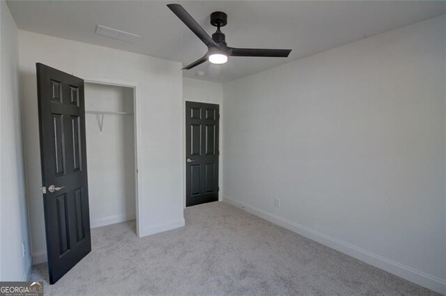 unfurnished bedroom featuring ceiling fan, a closet, and light colored carpet