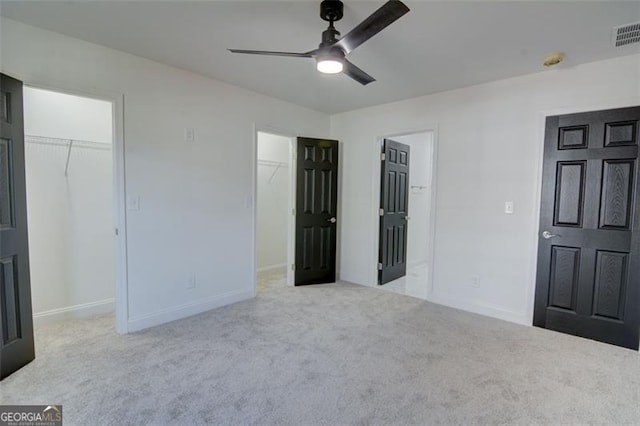 unfurnished bedroom featuring light colored carpet, a spacious closet, and ceiling fan