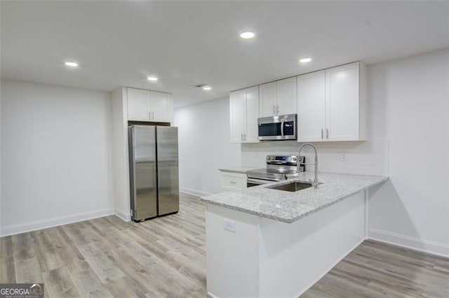 kitchen featuring sink, stainless steel appliances, light stone counters, white cabinets, and light wood-type flooring