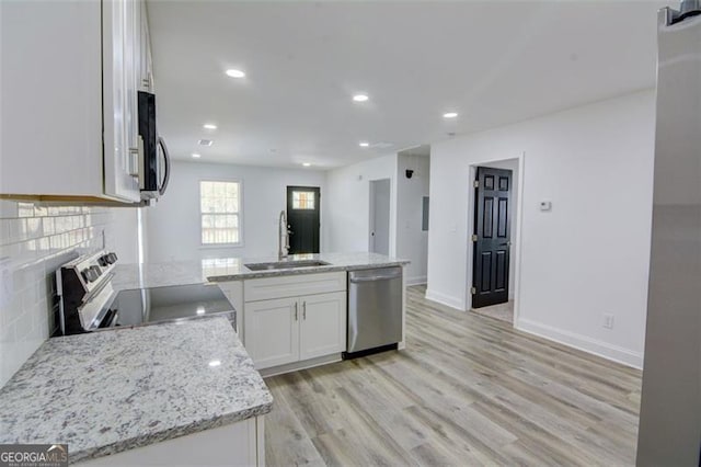 kitchen with white cabinetry, sink, light stone counters, appliances with stainless steel finishes, and light wood-type flooring