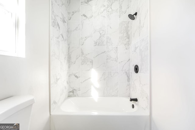 bathroom featuring toilet and tiled shower / bath combo