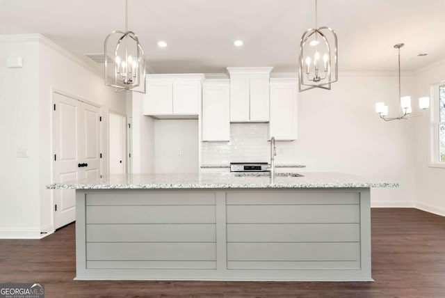 kitchen with light stone counters, white cabinets, and hanging light fixtures