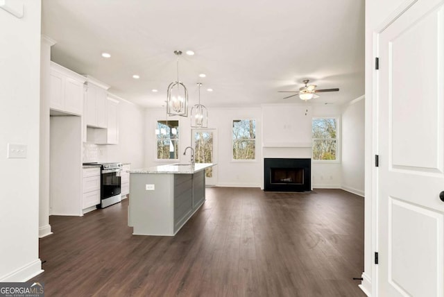 kitchen with white cabinetry, light stone countertops, decorative light fixtures, a center island with sink, and stainless steel stove