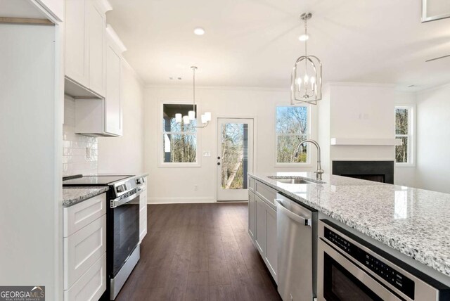 kitchen with light stone countertops, appliances with stainless steel finishes, white cabinetry, and sink