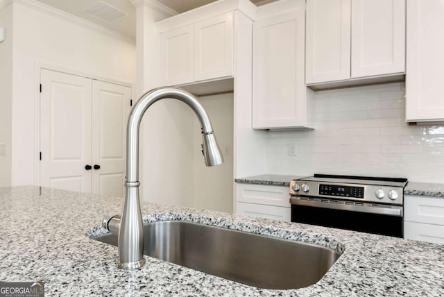 kitchen featuring light stone countertops, tasteful backsplash, white cabinetry, and stainless steel range with electric stovetop