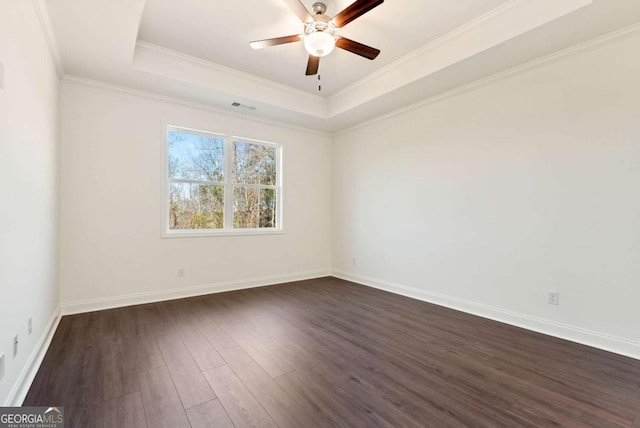 empty room with a tray ceiling, crown molding, dark hardwood / wood-style flooring, and ceiling fan