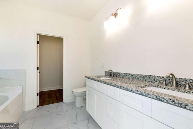 bathroom featuring vanity, toilet, and tiled bath