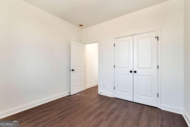 unfurnished bedroom with dark wood-type flooring and a closet