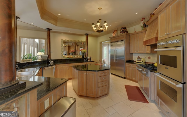 kitchen featuring decorative columns, a tray ceiling, pendant lighting, and appliances with stainless steel finishes