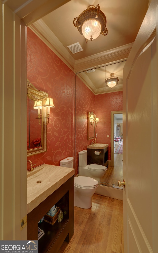 bathroom with hardwood / wood-style flooring, toilet, vanity, and ornamental molding