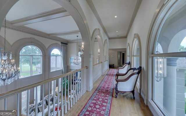 hallway with ornamental molding, light hardwood / wood-style floors, and a notable chandelier