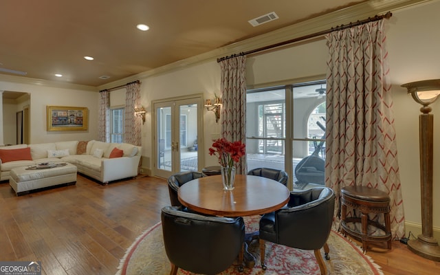 dining area with hardwood / wood-style flooring, crown molding, a wealth of natural light, and french doors