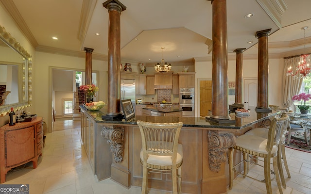 kitchen featuring a notable chandelier, a kitchen breakfast bar, hanging light fixtures, and decorative columns