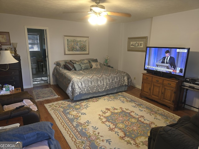 bedroom with connected bathroom, ceiling fan, and dark hardwood / wood-style flooring