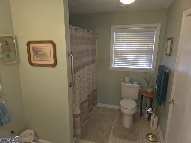 bathroom with a shower with shower curtain and toilet