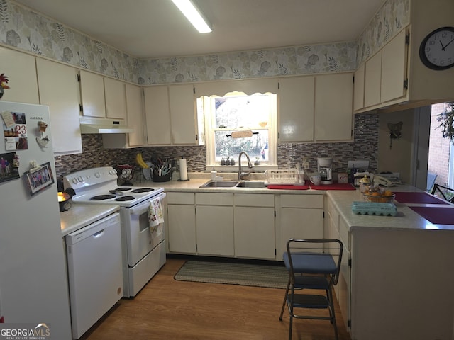 kitchen with backsplash, light wood-type flooring, white appliances, and sink