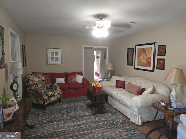 living room with ceiling fan and a textured ceiling