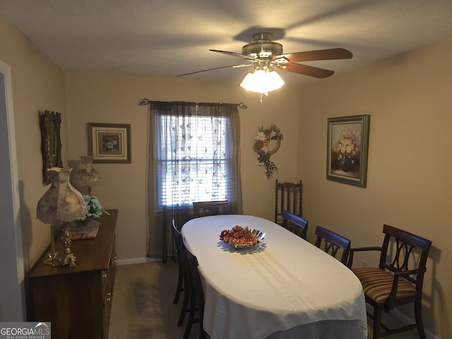 dining room with ceiling fan and dark carpet