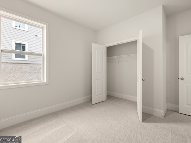 unfurnished bedroom featuring a closet and light colored carpet