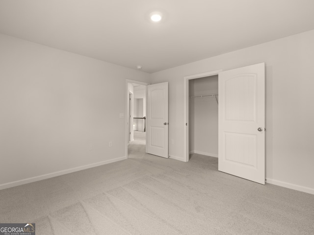 unfurnished bedroom featuring light colored carpet and a closet