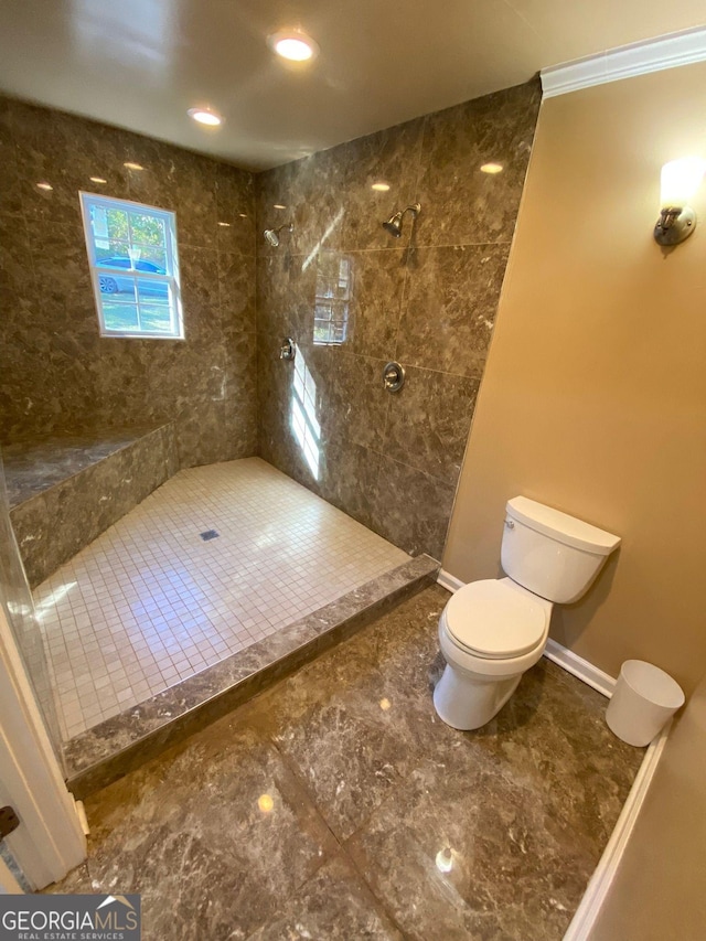 bathroom with tiled shower, toilet, and ornamental molding