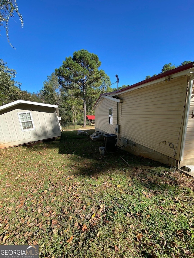 view of side of home with central AC unit and a yard