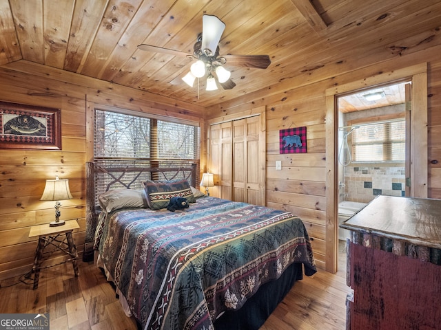 bedroom with wood walls, ceiling fan, light hardwood / wood-style floors, wood ceiling, and a closet