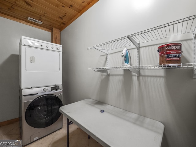 washroom with tile patterned floors, stacked washer and dryer, and wood ceiling