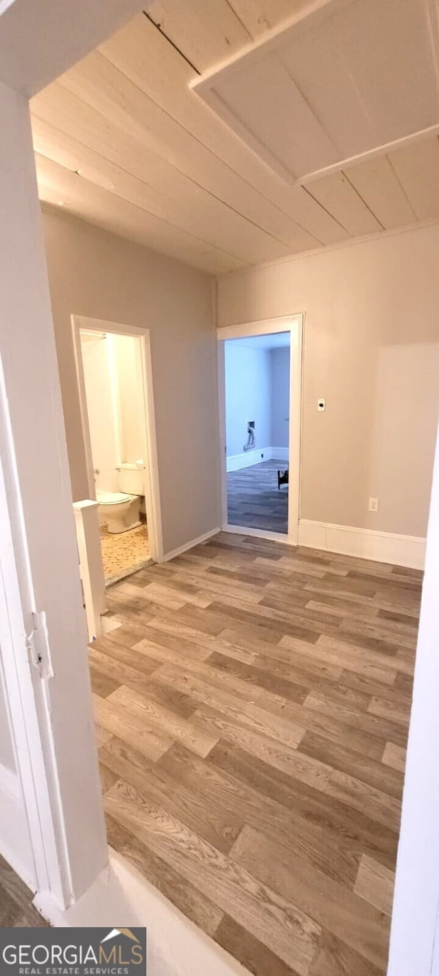 corridor featuring wood finished floors and baseboards