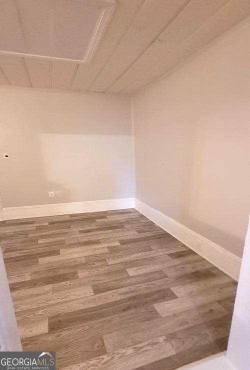 spare room with baseboards and wood finished floors