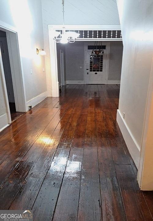 interior space featuring hardwood / wood-style floors, baseboards, and a chandelier