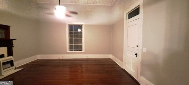 below grade area with heating unit, baseboards, ceiling fan, and dark wood-style flooring