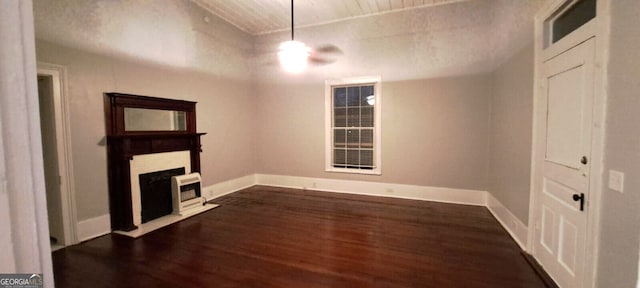 unfurnished living room featuring dark wood finished floors, a fireplace with flush hearth, and baseboards