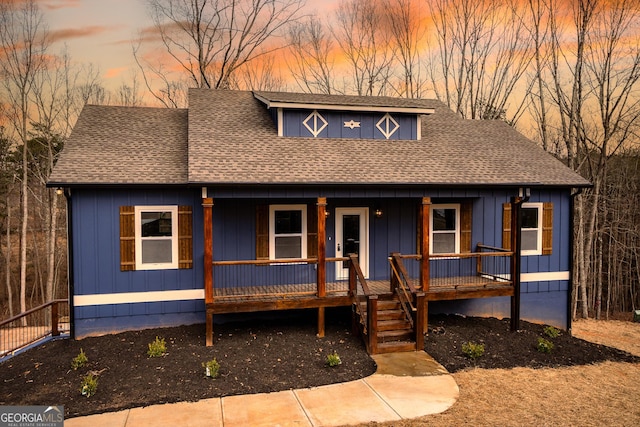 view of front of house with board and batten siding, covered porch, and a shingled roof