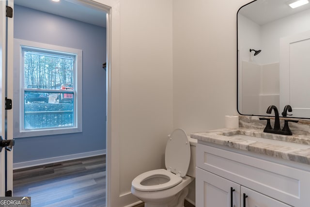 bathroom with visible vents, toilet, wood finished floors, baseboards, and vanity