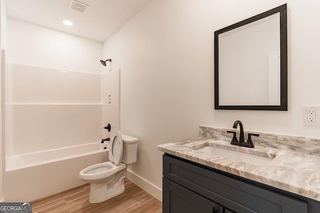 bathroom featuring visible vents, toilet, wood finished floors, washtub / shower combination, and vanity