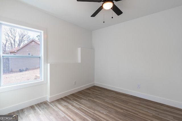 spare room with baseboards, wood finished floors, and a ceiling fan