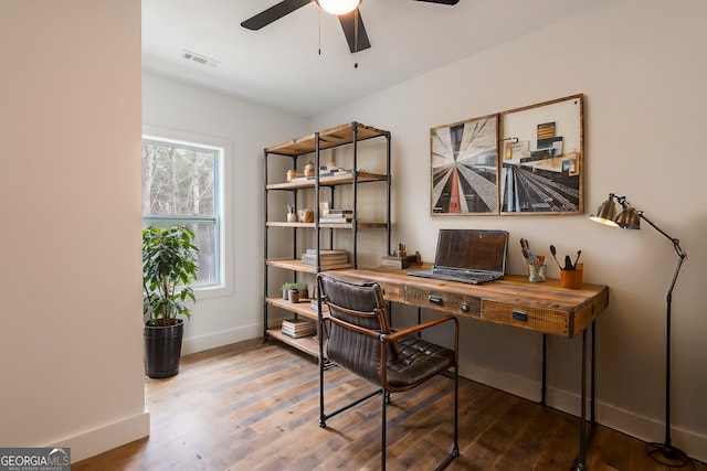 office space featuring a ceiling fan, wood finished floors, visible vents, and baseboards