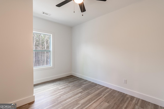 spare room featuring baseboards, visible vents, light wood finished floors, and ceiling fan