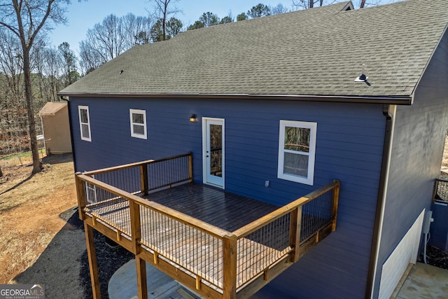 back of house featuring roof with shingles and a deck