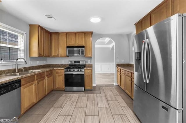 kitchen with dark stone counters, sink, and stainless steel appliances