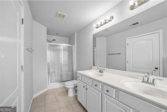 bathroom featuring tile patterned flooring, vanity, toilet, and a shower with door