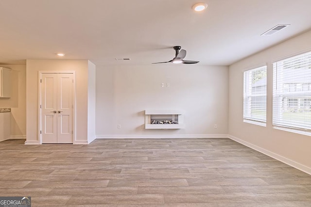 unfurnished living room with light wood-type flooring and ceiling fan