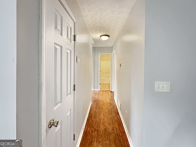 hallway featuring hardwood / wood-style floors and a textured ceiling