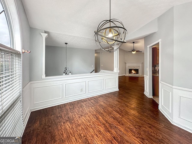 interior space featuring ceiling fan with notable chandelier, a textured ceiling, vaulted ceiling, and dark wood-type flooring