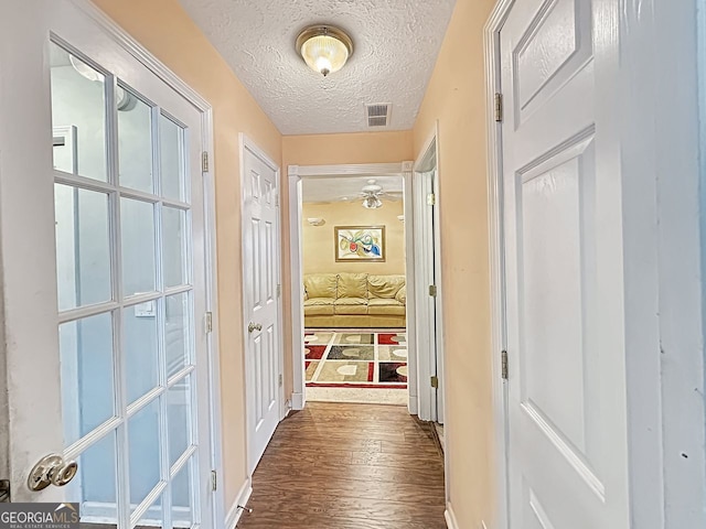 hallway with dark hardwood / wood-style floors and a textured ceiling