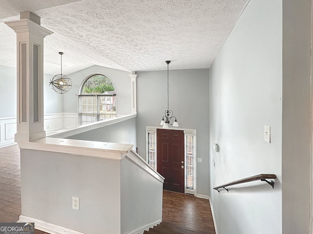 entrance foyer with a textured ceiling, dark hardwood / wood-style floors, lofted ceiling, and an inviting chandelier