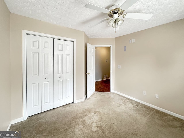 unfurnished bedroom with ceiling fan, carpet floors, a textured ceiling, and a closet