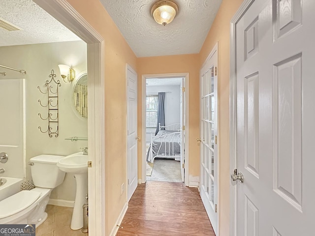 full bathroom featuring a textured ceiling,  shower combination, hardwood / wood-style flooring, and toilet