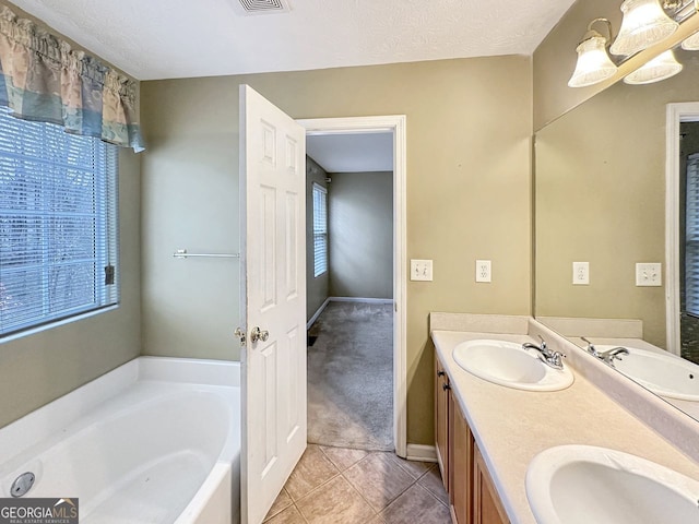 bathroom featuring tile patterned floors, vanity, a bath, and a textured ceiling